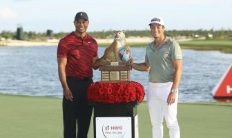 Tiger Woods handing over the winning trophy to Viktor Hovland